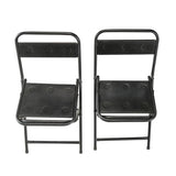 A pair of folding chairs with black leather cushions. - Deszine Talks